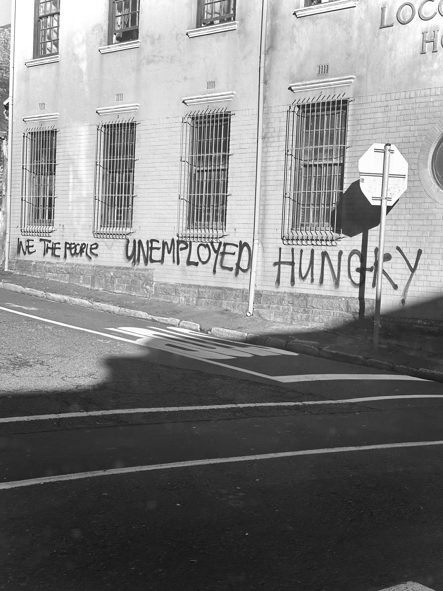 a black and white image of graffiti that reads "we the people unemployed hungry" on a building 